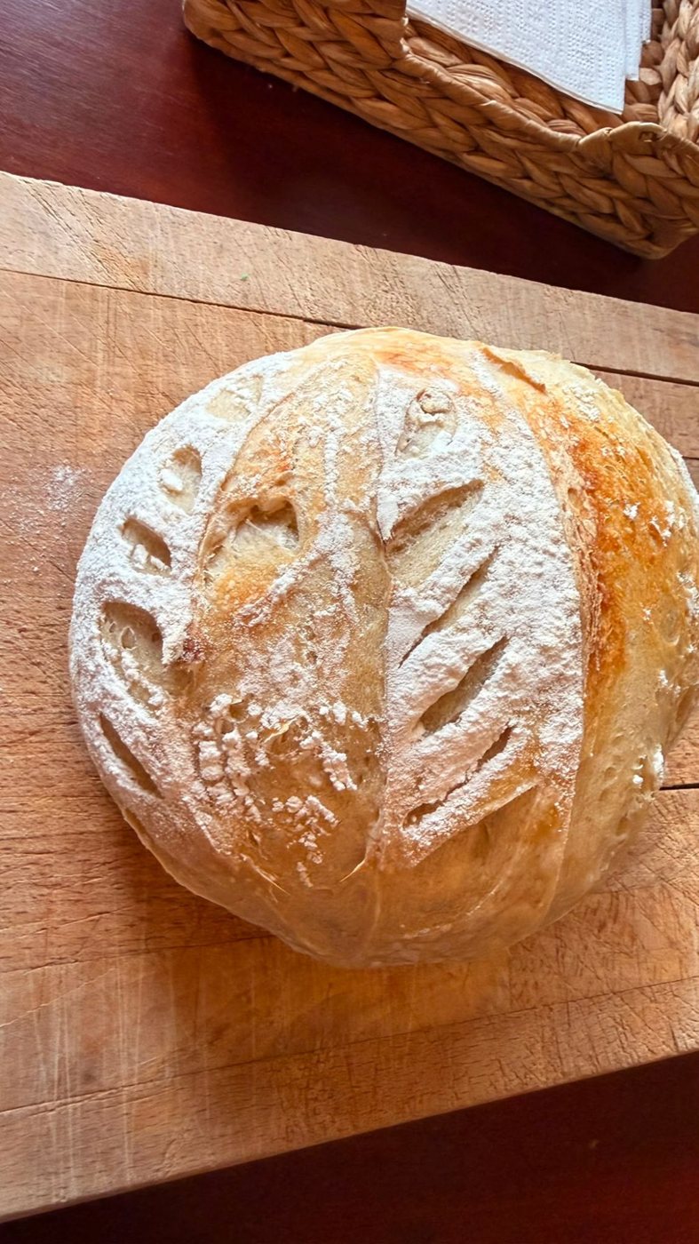 Scored sourdough loaf with a wheat pattern, baked by an Aterra Mills customer with our flour